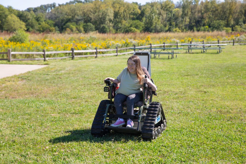a person using an all-terrain wheelchair to navigate through an open grass area