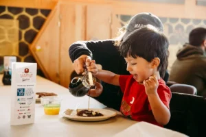 Boy smiles as maple syrup poured on his pancakes